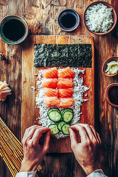 After view of a chef’s hands meticulously crafting sushi on a rustic wooden board