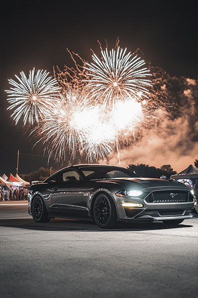 Before Ford Mustang GT parked near a carnival, a massive fireworks display exploding in the sky