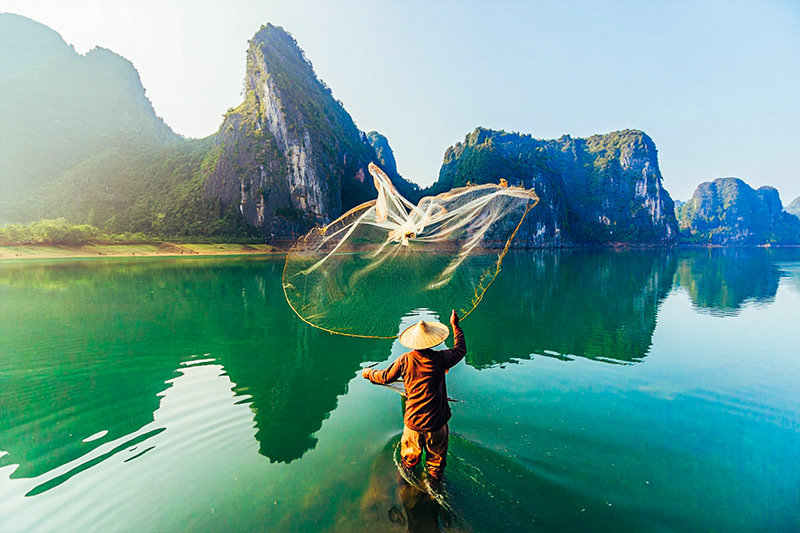 After fisherman stands in ankle-deep water while casting a circular fishing net