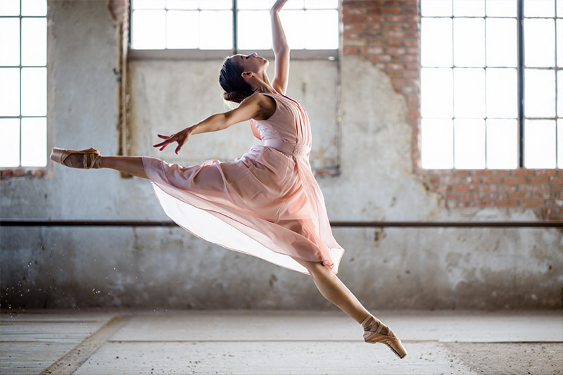 Before female ballet dancer in her early twenties performs a grand jeté leap