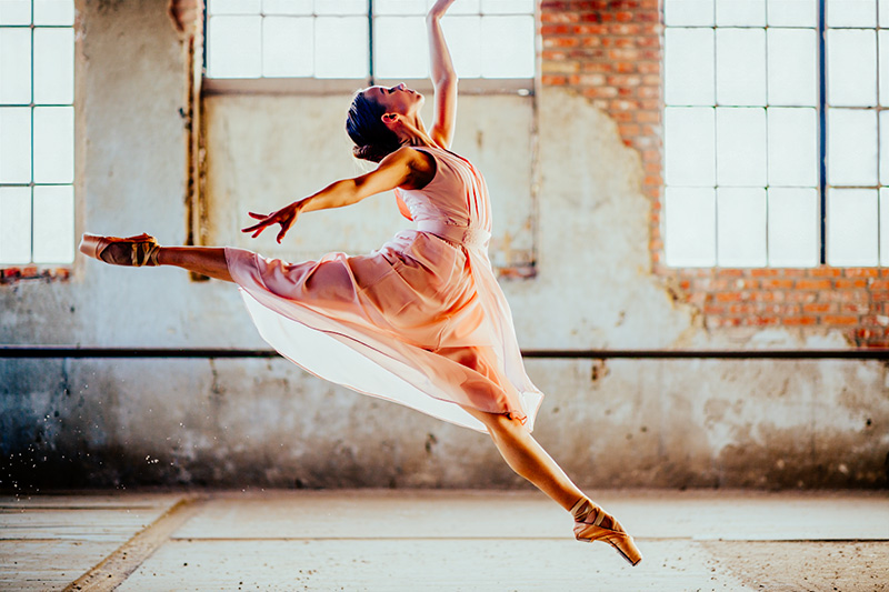 After female ballet dancer in her early twenties performs a grand jeté leap