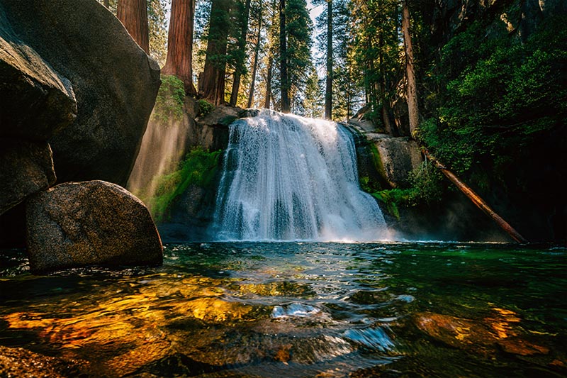 After waterfall in Yosemite National Park, California, shows cascading white water dropping into a crystal-clear pool below
