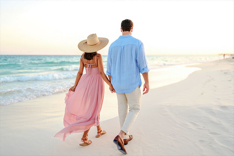 Before couple walking hand in hand on the white sands of Playa del Carmen