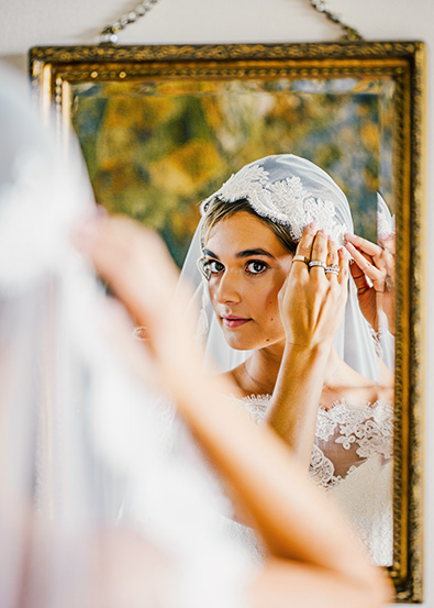 After close-up photograph shows a bride's hands wearing multiple rings