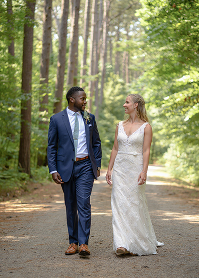 Before wedding couple walking side by side down a dirt path through a sunlit forest