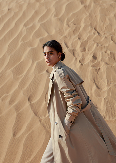 Before fashion model walks across golden sand dunes