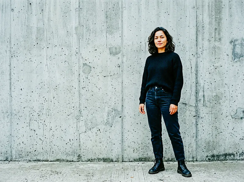Portrait of model in black clothing against stone wall architecture edited with Kodak Ektachrome E100 Lightroom preset showing precise contrast and cool accurate tones