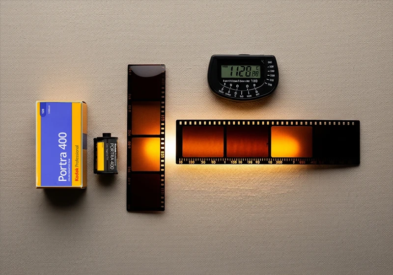 Kodak Portra 400 35mm film roll beside medium format 120 negative strip on cream linen"